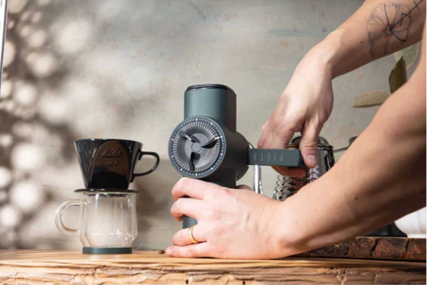 Individual using their hands, cranking a hinge on the coffee grinder.