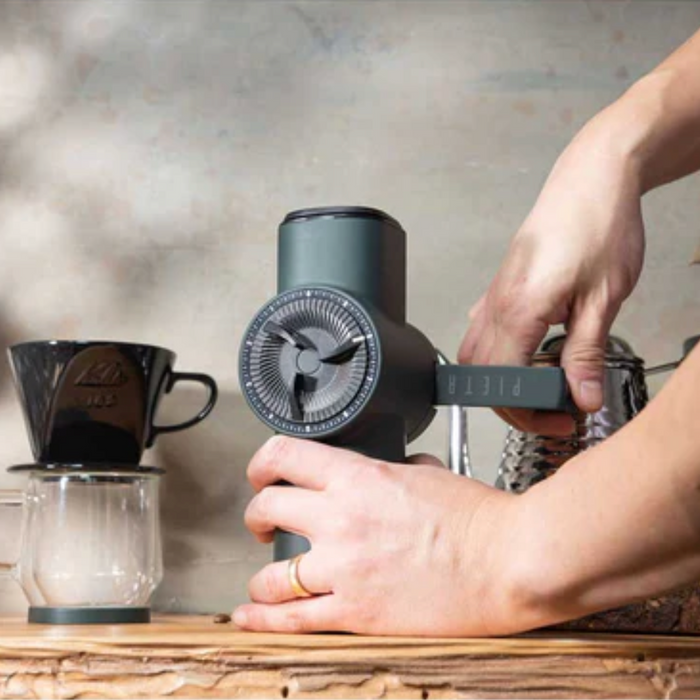 Individual using their hands, cranking a hinge on the coffee grinder.